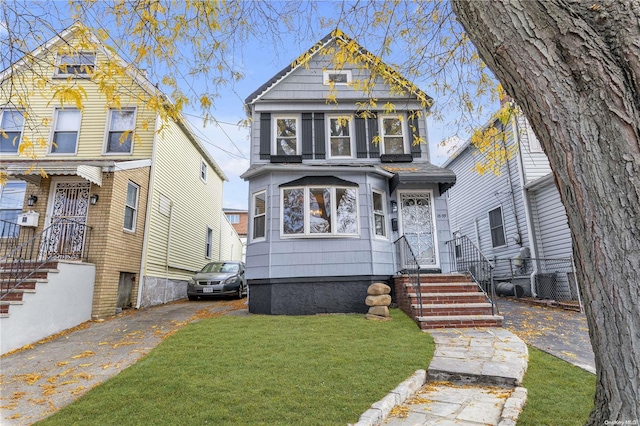 victorian home with central air condition unit and a front lawn