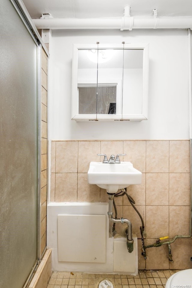 bathroom with an enclosed shower, tile walls, and sink