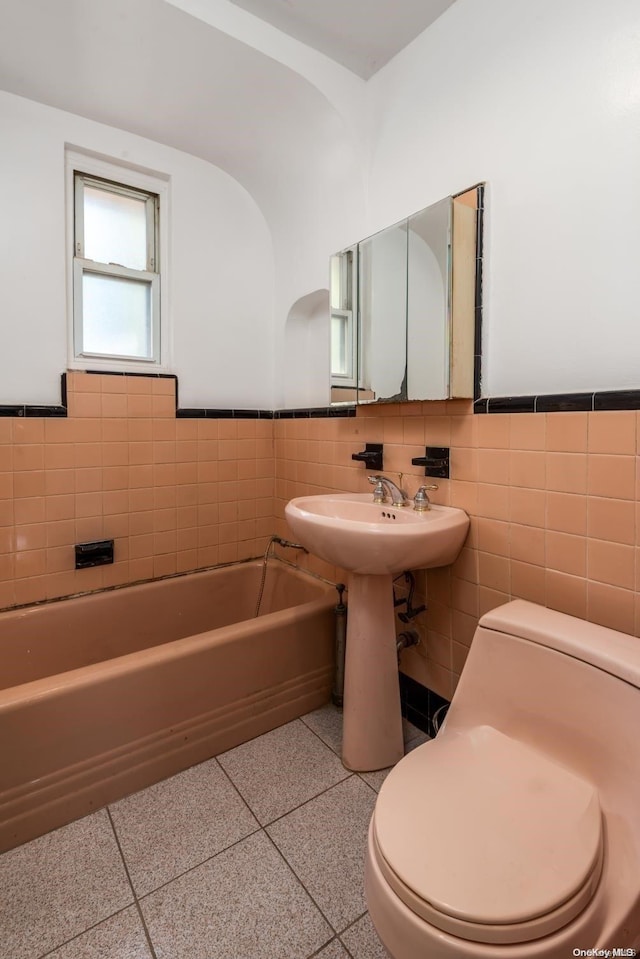 bathroom featuring a washtub, tile walls, and toilet