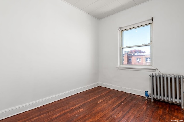 empty room with dark hardwood / wood-style flooring and radiator