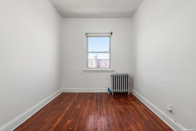 spare room with dark wood-type flooring and radiator