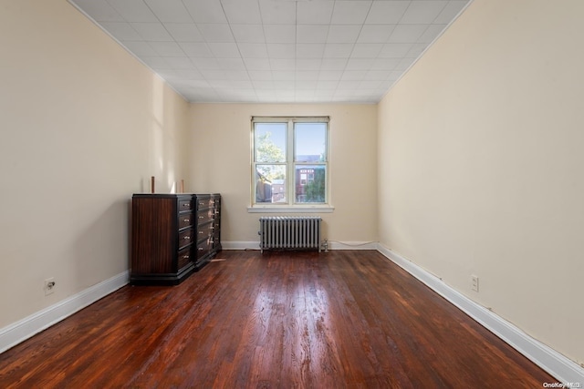 spare room featuring radiator heating unit and dark wood-type flooring