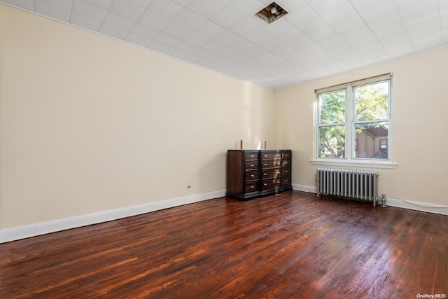 spare room featuring dark hardwood / wood-style floors and radiator heating unit