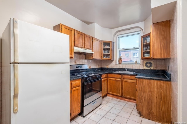 kitchen featuring decorative backsplash, sink, white fridge, and stainless steel gas range