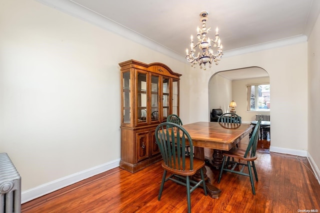 dining space featuring hardwood / wood-style flooring, ornamental molding, and a notable chandelier