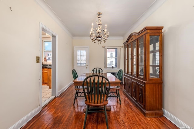 dining space with crown molding, dark wood-type flooring, and an inviting chandelier