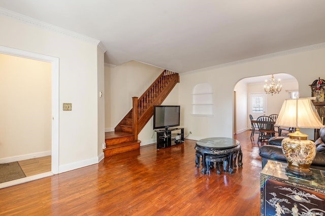 living room featuring wood-type flooring, crown molding, and a chandelier