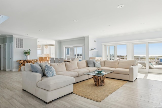 living room featuring plenty of natural light, ornamental molding, and light wood-type flooring