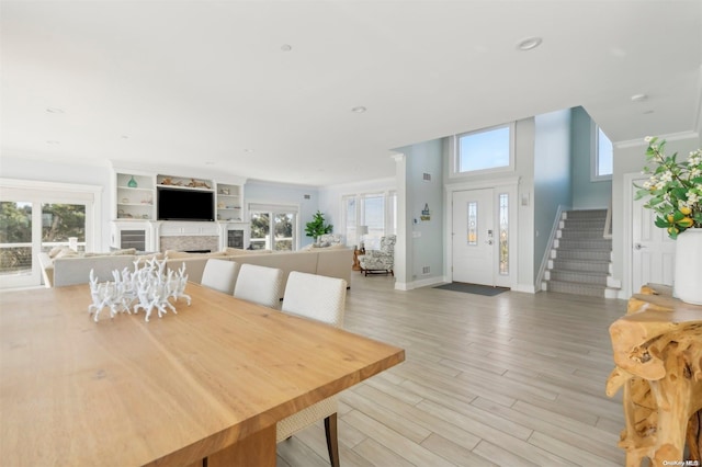 dining room with a wealth of natural light, crown molding, and light wood-type flooring