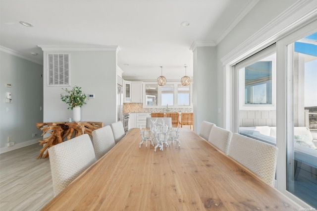 dining area featuring light wood-type flooring, plenty of natural light, and ornamental molding