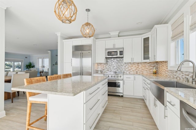 kitchen featuring white cabinets, a breakfast bar area, decorative light fixtures, a kitchen island, and stainless steel appliances