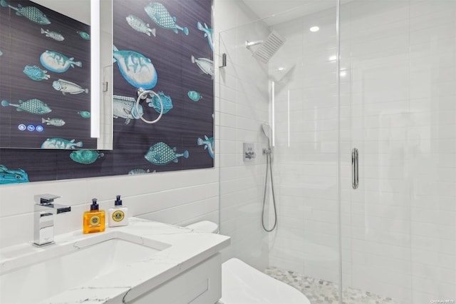 bathroom featuring an enclosed shower, vanity, toilet, and tile walls