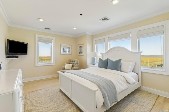 bedroom featuring light wood-type flooring, multiple windows, and ornamental molding