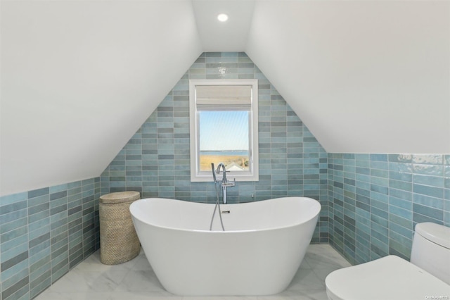 bathroom with a bath, toilet, lofted ceiling, and tile walls