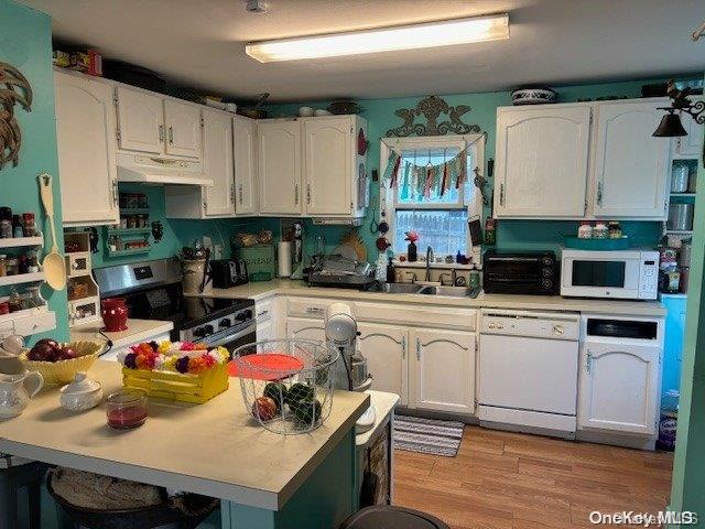 kitchen with extractor fan, white appliances, white cabinetry, and sink