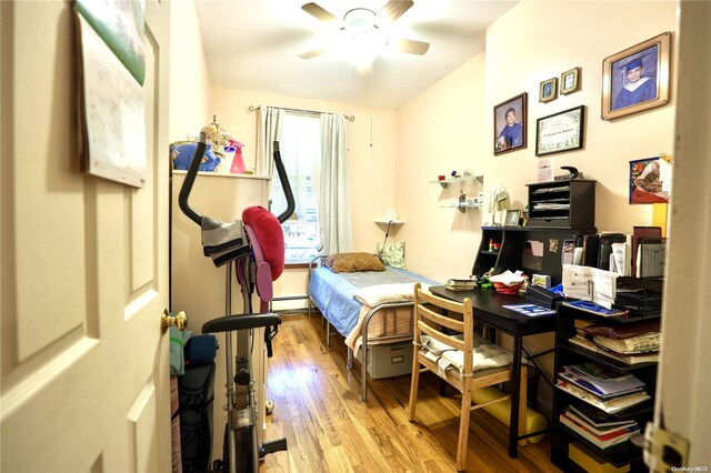 bedroom with light wood-type flooring, baseboard heating, and ceiling fan