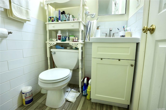 bathroom with wood-type flooring, vanity, toilet, and tile walls