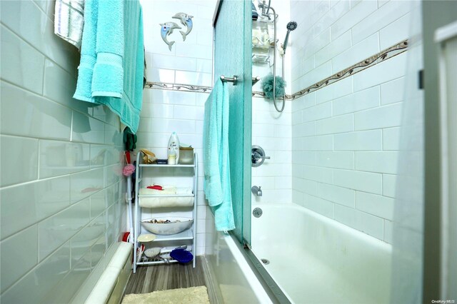 bathroom with hardwood / wood-style flooring, tiled shower / bath, and tile walls