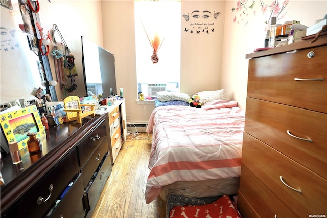 bedroom featuring cooling unit, a baseboard radiator, and light wood-type flooring