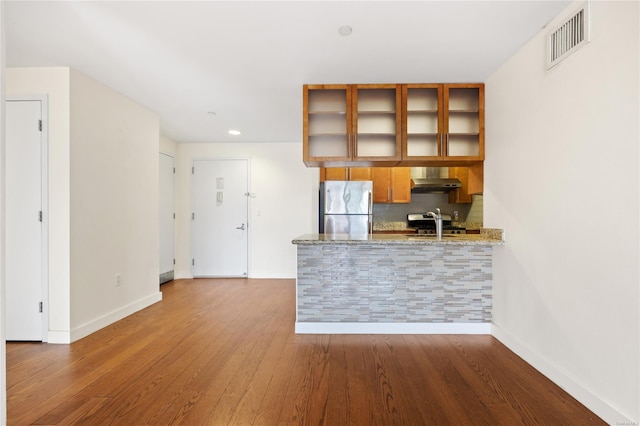 kitchen with appliances with stainless steel finishes, tasteful backsplash, sink, hardwood / wood-style flooring, and light stone counters