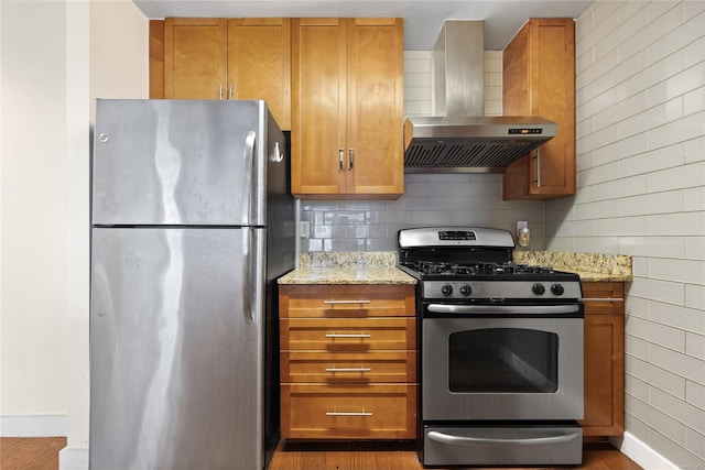 kitchen featuring extractor fan, decorative backsplash, light stone counters, stainless steel appliances, and light wood-type flooring