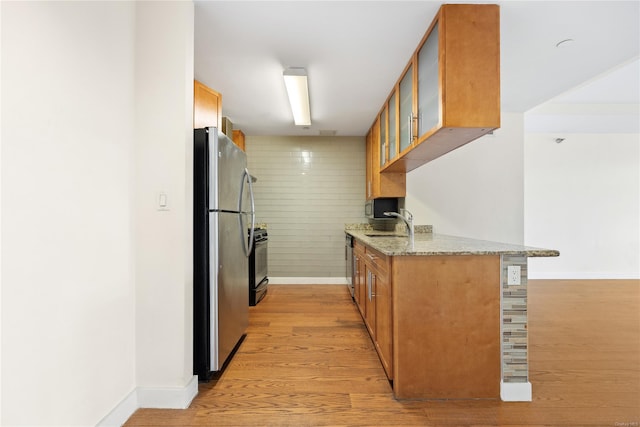 kitchen featuring sink, light hardwood / wood-style flooring, appliances with stainless steel finishes, light stone countertops, and kitchen peninsula