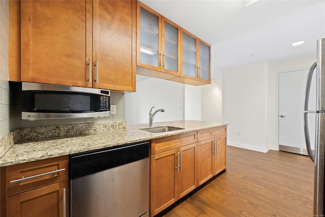 kitchen featuring light stone counters, sink, light hardwood / wood-style floors, and appliances with stainless steel finishes