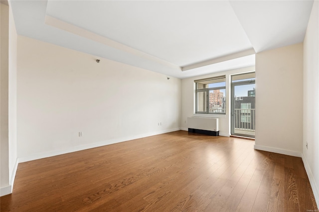 unfurnished living room with radiator, hardwood / wood-style floors, and a raised ceiling