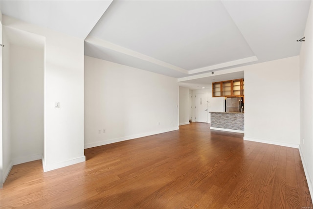 unfurnished living room with hardwood / wood-style flooring and a tray ceiling