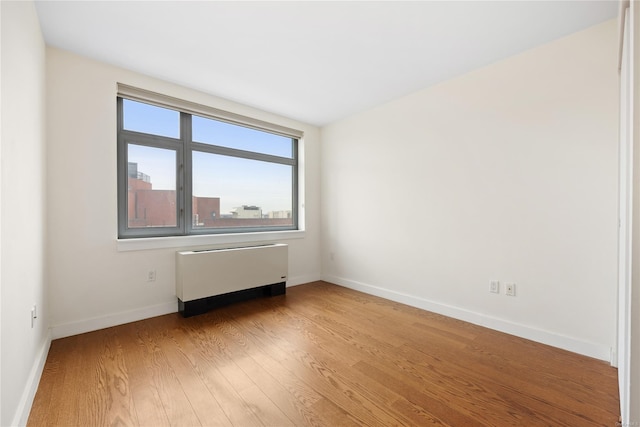 unfurnished room with radiator and light wood-type flooring