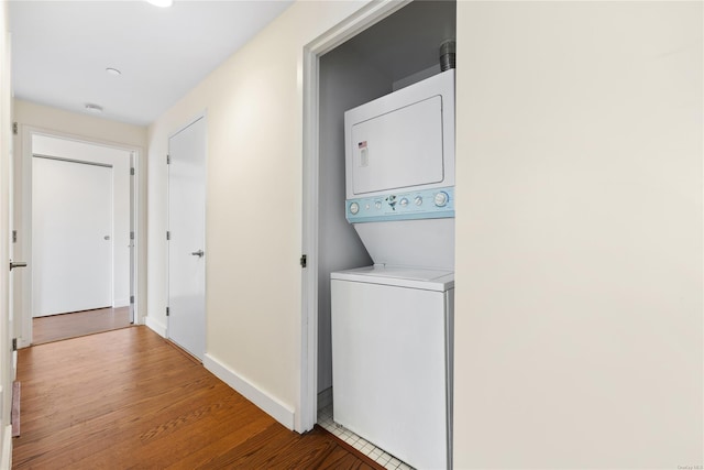 laundry area with stacked washer / drying machine and light hardwood / wood-style flooring