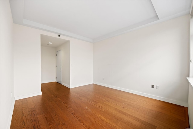 unfurnished room with hardwood / wood-style flooring and a raised ceiling