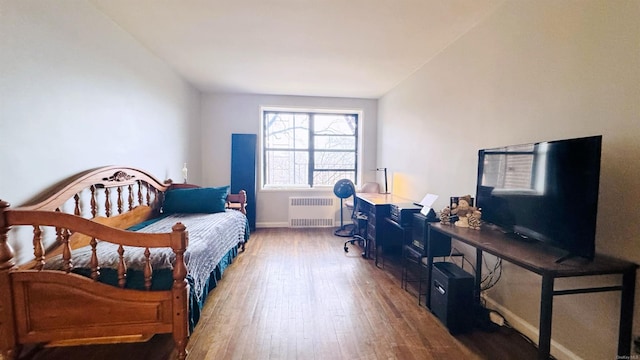 bedroom featuring radiator heating unit and dark hardwood / wood-style flooring