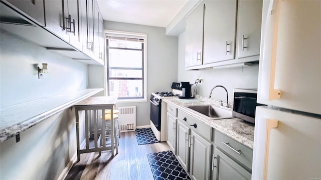 kitchen featuring white appliances, radiator, sink, light stone countertops, and dark hardwood / wood-style flooring