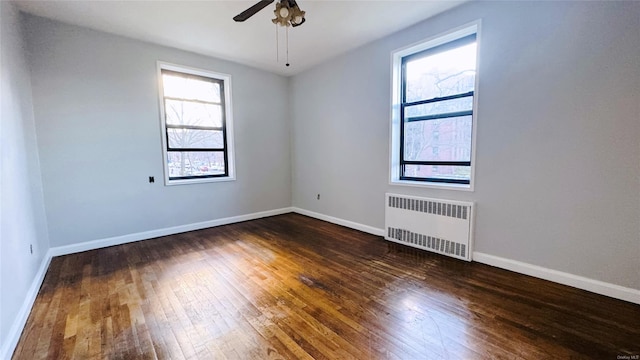 empty room featuring radiator heating unit, ceiling fan, and dark wood-type flooring