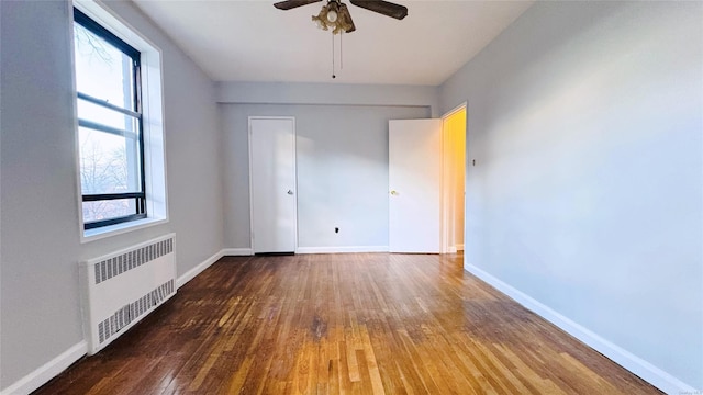 empty room with radiator heating unit, ceiling fan, and wood-type flooring