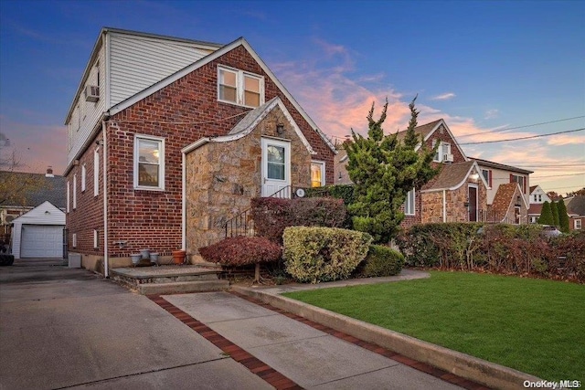 tudor-style house with a yard, an outdoor structure, and a garage