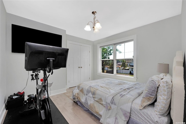 bedroom featuring wood-type flooring, a closet, and a notable chandelier