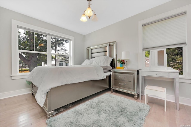 bedroom with a chandelier, light hardwood / wood-style flooring, and multiple windows