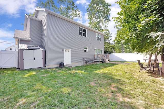 back of house featuring a storage shed, a deck, and a yard