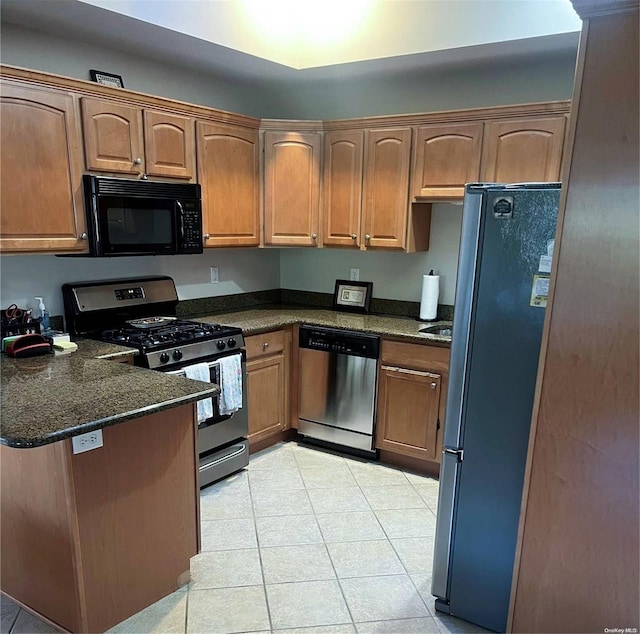 kitchen featuring dark stone countertops, light tile patterned floors, and black appliances