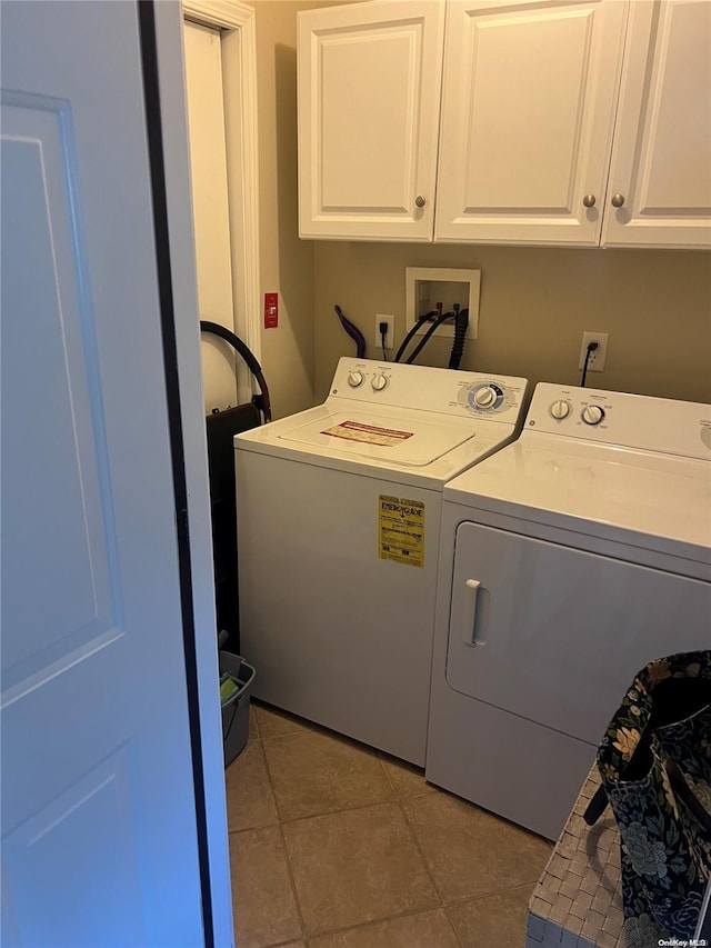 laundry area featuring washing machine and clothes dryer, tile patterned floors, and cabinets