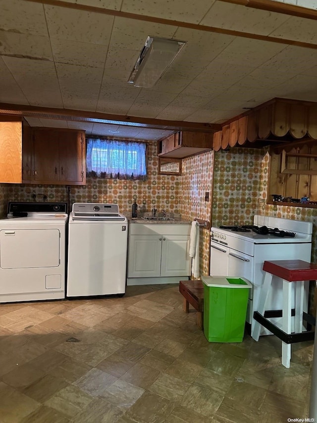 clothes washing area with washing machine and clothes dryer and sink