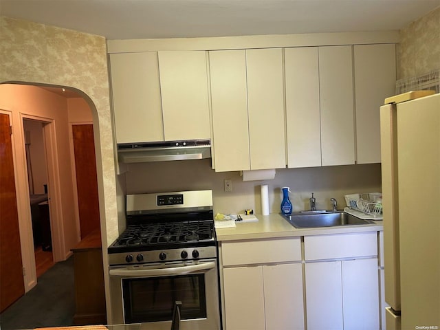 kitchen featuring gas stove, white cabinetry, sink, and white refrigerator