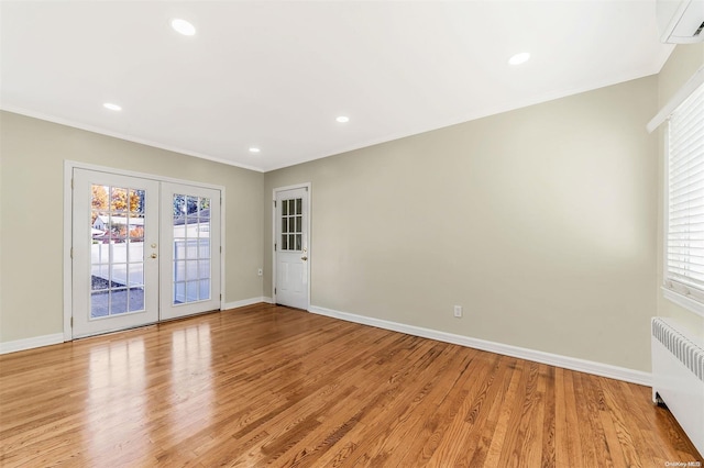 spare room featuring radiator, a wealth of natural light, french doors, and light hardwood / wood-style flooring