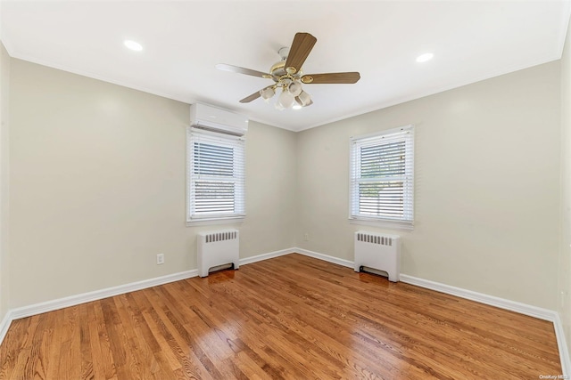 spare room featuring hardwood / wood-style flooring, radiator heating unit, crown molding, and a wall unit AC