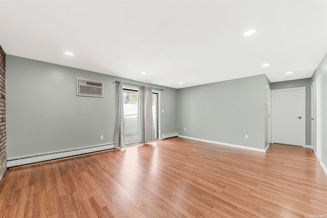 spare room featuring a baseboard radiator, light hardwood / wood-style flooring, and an AC wall unit