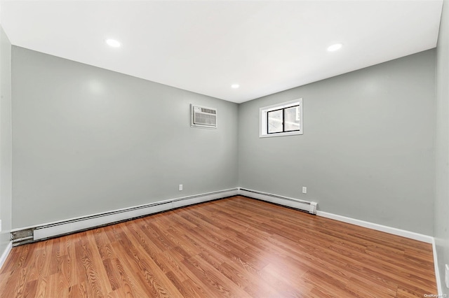 unfurnished room with light wood-type flooring, a wall unit AC, and a baseboard heating unit