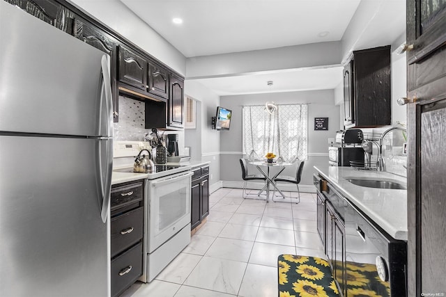 kitchen with tasteful backsplash, sink, electric stove, decorative light fixtures, and stainless steel refrigerator