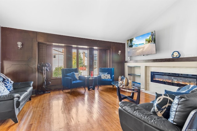 living room with light hardwood / wood-style floors, wooden walls, and vaulted ceiling